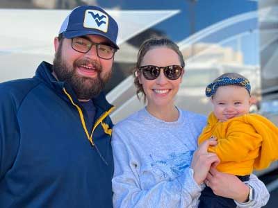 Hannah Booth with her husband and baby at a WVU football game.