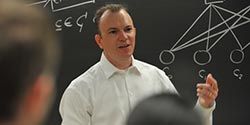 Male professor standing in front of a chalkboard.