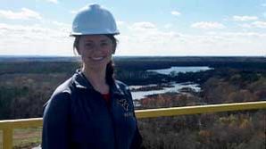 Adison Nordstrom wearing a hard hat in front of surveyed land.