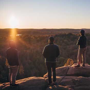 JuHyeong Ryu with friends watching a sunset at the top of a mountain.