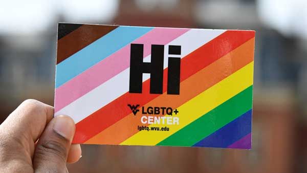LGBTQ card being held up in front of Woodburn Hall.