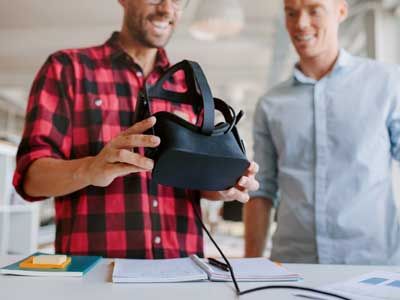 Two men using virtual reality goggles in office.