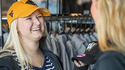 Woman wearing a WVU hat and thinking about buying a West Virginia Black Bears hat.