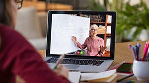Female teacher on a screen, teaching virtually.