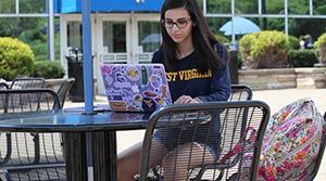 Nicole Andino working on her laptop in front of the Mountainlair.