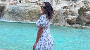 Marilyn Espinal wearing a dress and standing in front of blue water.