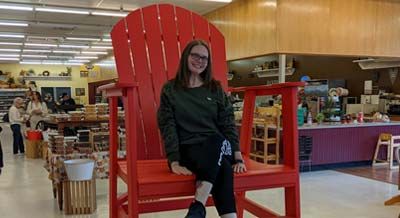 Pam McDonald sitting in an oversized, red chair.
