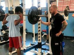 Ryan Wood helping a fellow student lift weights.
