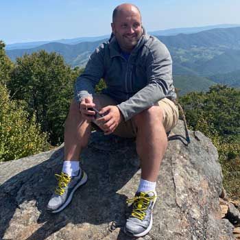 Corey Edmonds sitting on a rock after hiking.