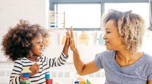 Young female child and female adult high-fiving.
