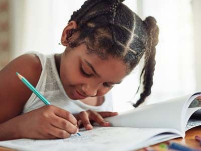 Young female child drawing in a book.