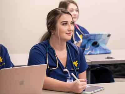 Two female WVU nursing students listening to a lecture.