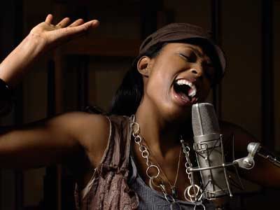 Young woman singing into a microphone.