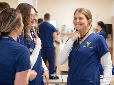 Three female WVU nursing students talking in a hospital.